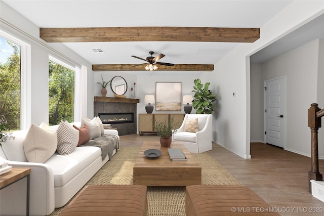 living room featuring beamed ceiling, ceiling fan, and light wood-type flooring