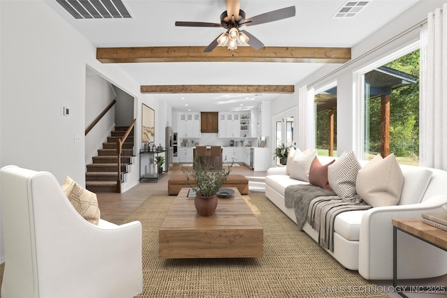 living room with hardwood / wood-style flooring, ceiling fan, and beam ceiling