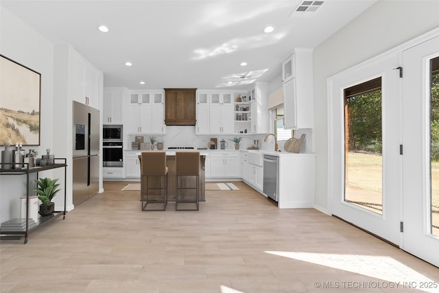 kitchen featuring a breakfast bar, tasteful backsplash, a kitchen island, stainless steel appliances, and white cabinets