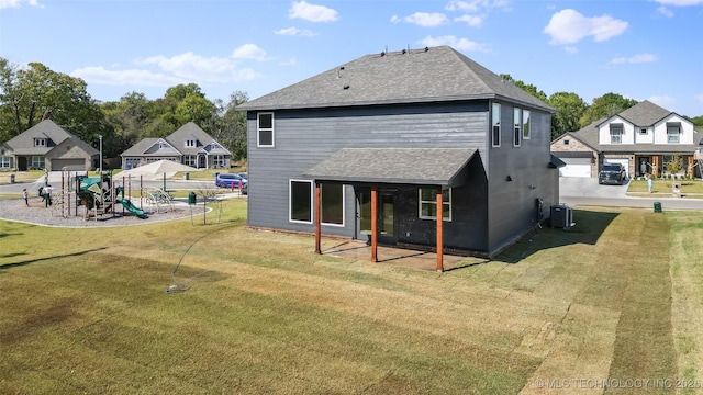 rear view of house with central AC, a yard, and a playground