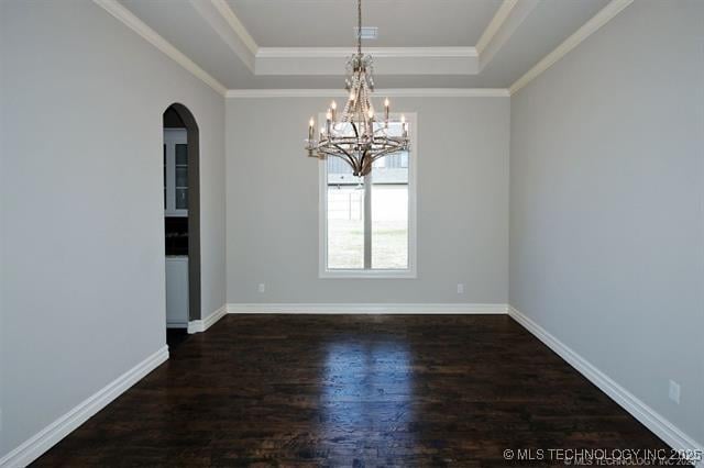 empty room with a notable chandelier, dark wood-type flooring, ornamental molding, and a raised ceiling