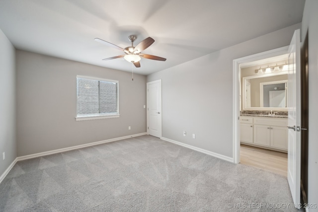 unfurnished bedroom featuring ceiling fan, sink, light colored carpet, and ensuite bath