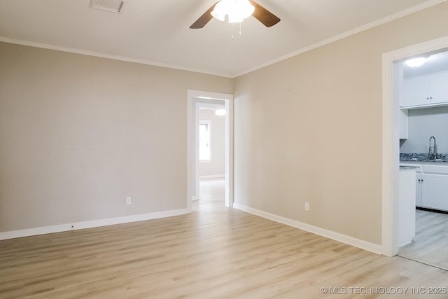 empty room featuring ceiling fan, ornamental molding, sink, and light hardwood / wood-style floors