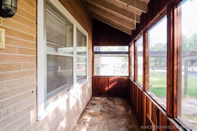 unfurnished sunroom featuring vaulted ceiling and plenty of natural light