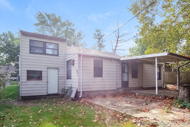 back of house with a carport and a yard