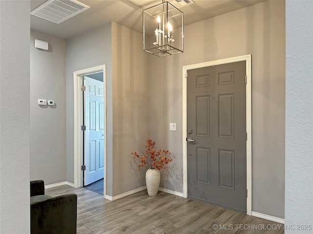 entryway with an inviting chandelier and light hardwood / wood-style flooring