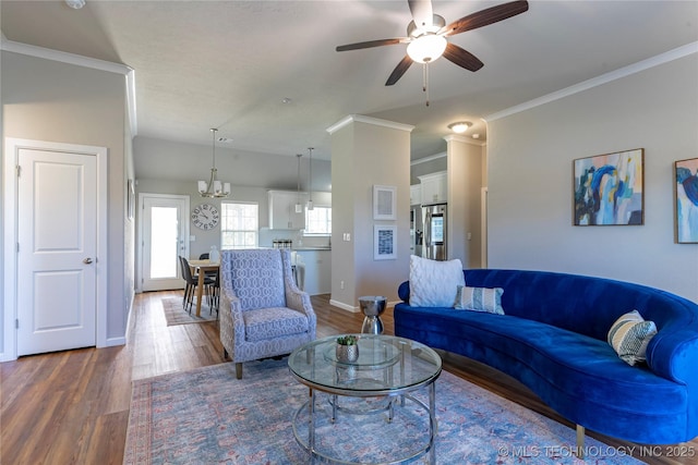 living room with crown molding, dark wood-type flooring, and ceiling fan with notable chandelier