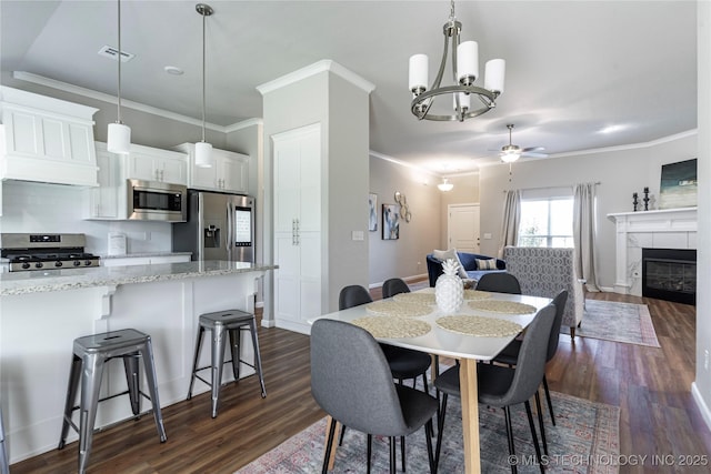 dining room featuring crown molding, dark hardwood / wood-style floors, ceiling fan, and a fireplace