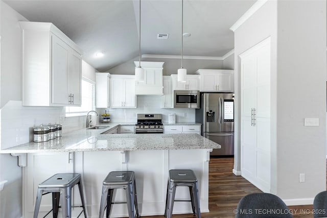 kitchen featuring stainless steel appliances, white cabinets, and a kitchen bar