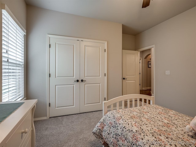 carpeted bedroom with ceiling fan and a closet