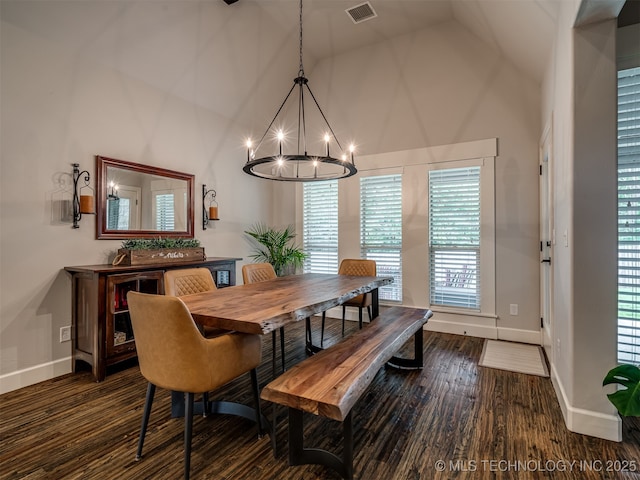 dining area with dark wood-type flooring, a notable chandelier, and high vaulted ceiling