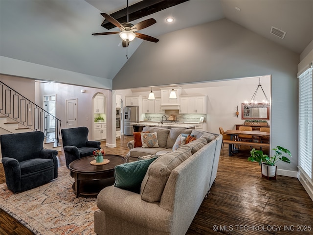 living room with dark wood-type flooring, high vaulted ceiling, sink, and ceiling fan with notable chandelier