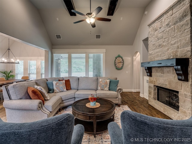 living room featuring a stone fireplace, plenty of natural light, dark hardwood / wood-style floors, and ceiling fan with notable chandelier