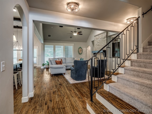 living room with ceiling fan with notable chandelier, wood-type flooring, and vaulted ceiling