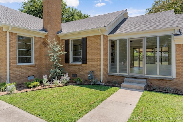 view of exterior entry with a yard