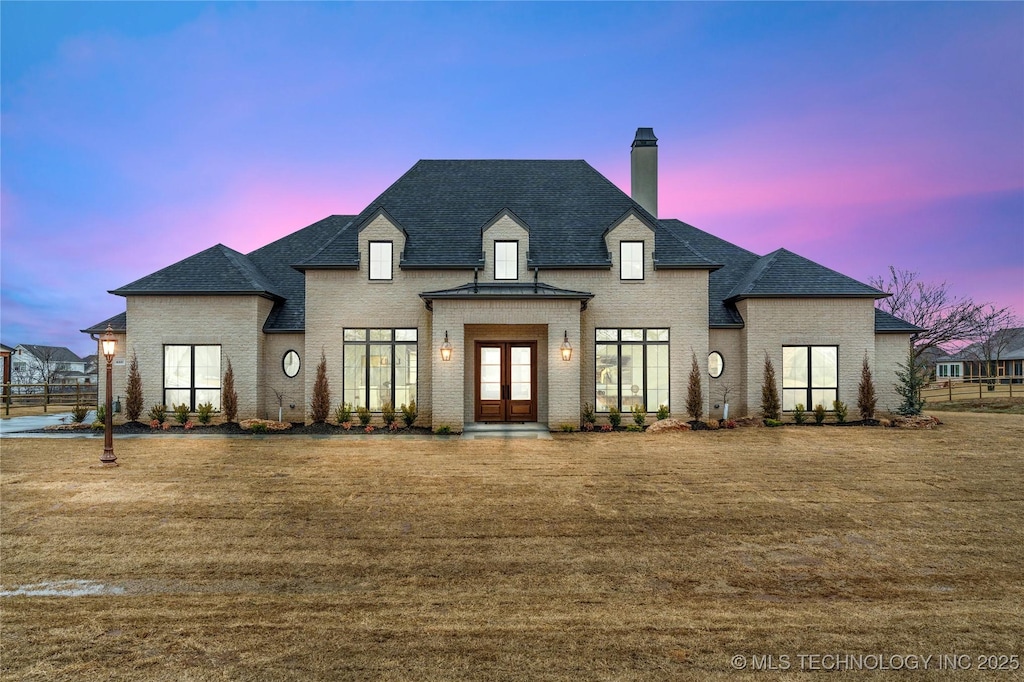 french provincial home with a lawn and french doors