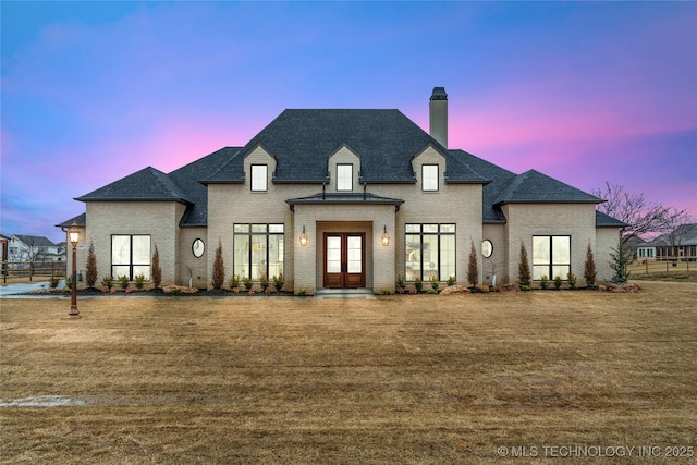 french provincial home with a lawn and french doors