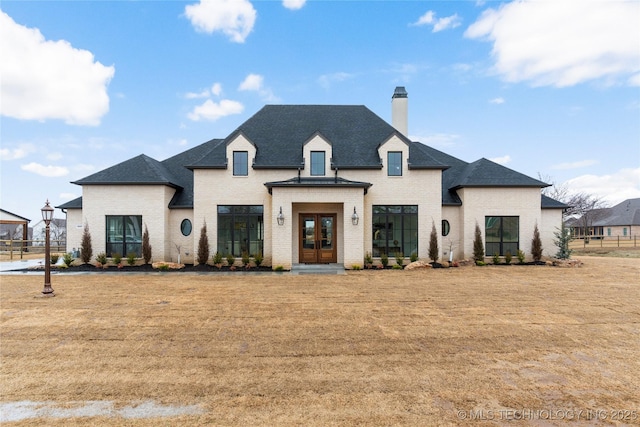 french country home with a front yard and french doors