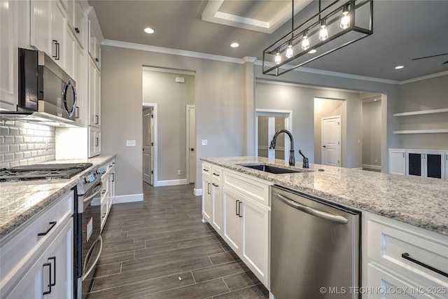 kitchen with sink, light stone counters, decorative light fixtures, appliances with stainless steel finishes, and white cabinets