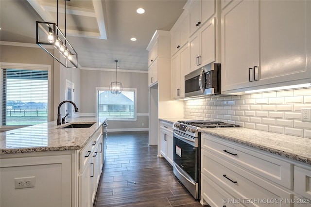 kitchen with appliances with stainless steel finishes, sink, white cabinets, hanging light fixtures, and light stone countertops