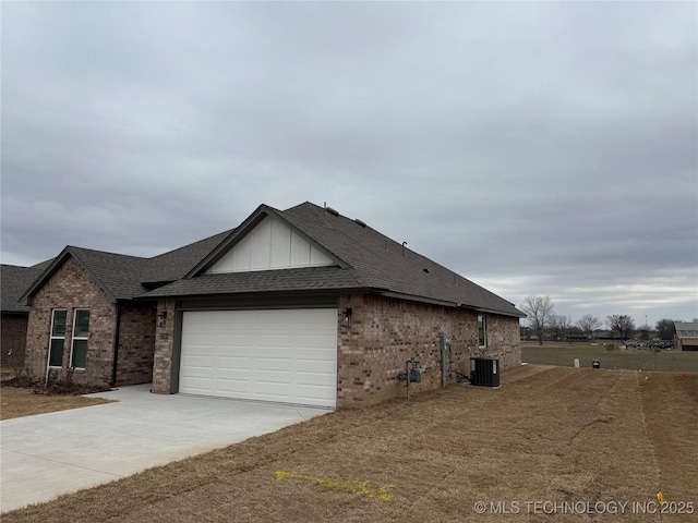 view of home's exterior featuring an attached garage, a shingled roof, central AC unit, and brick siding