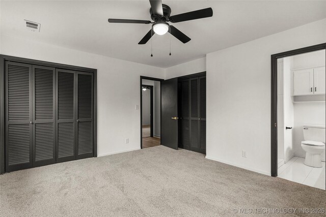 unfurnished bedroom featuring multiple closets, ceiling fan, connected bathroom, and light carpet