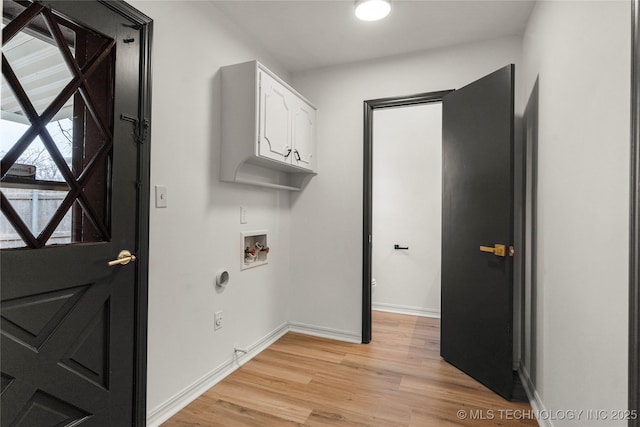 clothes washing area with washer hookup, light hardwood / wood-style flooring, and cabinets