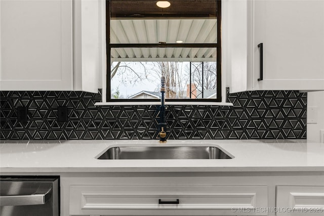 kitchen with dishwasher, white cabinetry, sink, and decorative backsplash