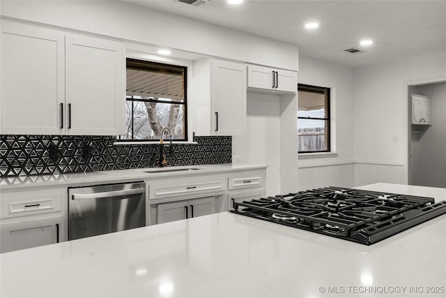 kitchen featuring sink, dishwasher, black gas cooktop, decorative backsplash, and white cabinets