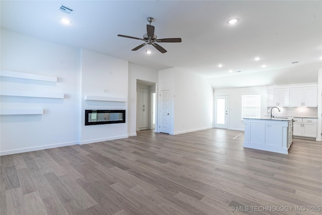 unfurnished living room featuring sink, light hardwood / wood-style flooring, and ceiling fan