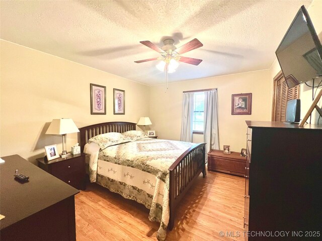 bedroom featuring ceiling fan, a textured ceiling, and light wood-type flooring