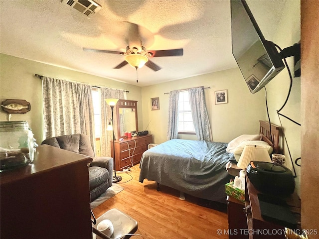 bedroom with ceiling fan, a textured ceiling, and light wood-type flooring