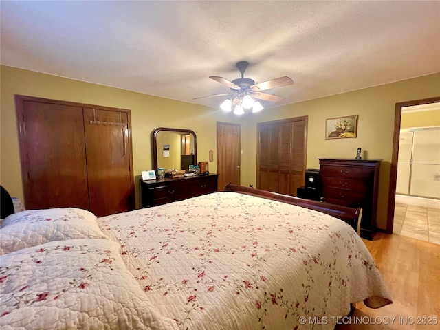 bedroom featuring connected bathroom, a textured ceiling, multiple closets, ceiling fan, and light hardwood / wood-style floors