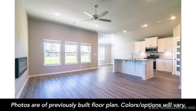 kitchen with dark wood-type flooring, white cabinetry, a center island with sink, stainless steel appliances, and backsplash