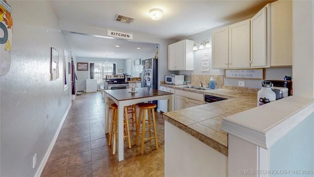 kitchen featuring stainless steel range with electric stovetop, sink, white cabinets, and a kitchen bar