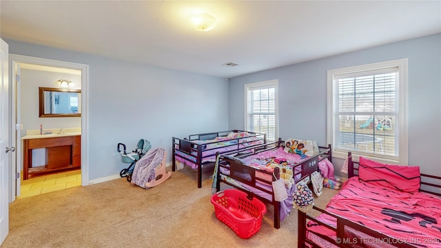 bedroom with connected bathroom and light carpet