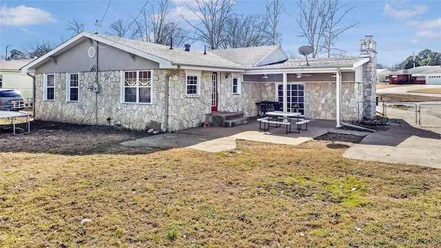 back of property with a trampoline, a patio, and a lawn