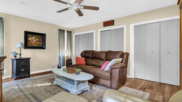 living room with dark wood-type flooring and ceiling fan