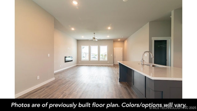 kitchen with sink, hardwood / wood-style floors, ceiling fan, and a center island with sink