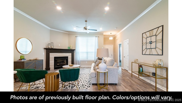 living room featuring light hardwood / wood-style flooring, ornamental molding, a tile fireplace, and ceiling fan