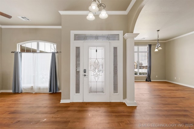 entryway with ornamental molding, wood-type flooring, a chandelier, and decorative columns