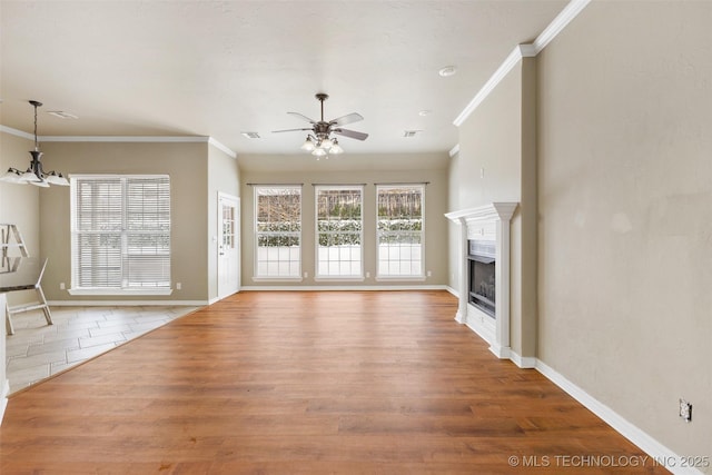 unfurnished living room with wood-type flooring, ceiling fan with notable chandelier, and crown molding