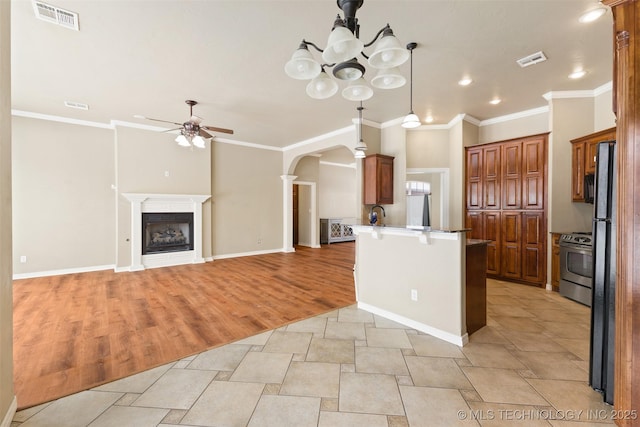 kitchen with a breakfast bar, ceiling fan with notable chandelier, hanging light fixtures, stainless steel range, and kitchen peninsula