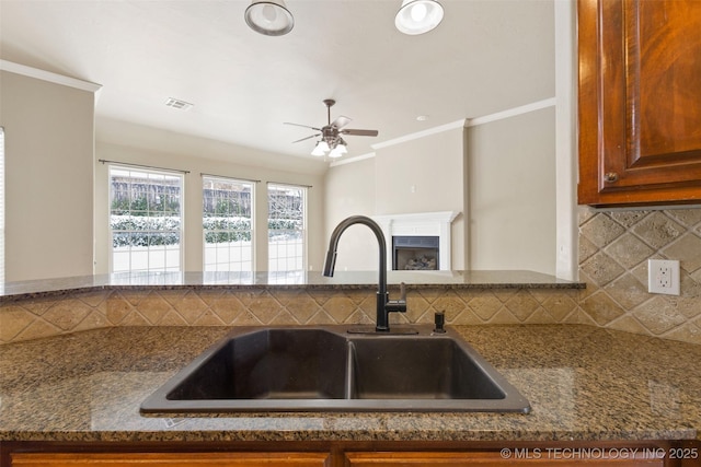 kitchen featuring crown molding, ceiling fan, sink, and decorative backsplash