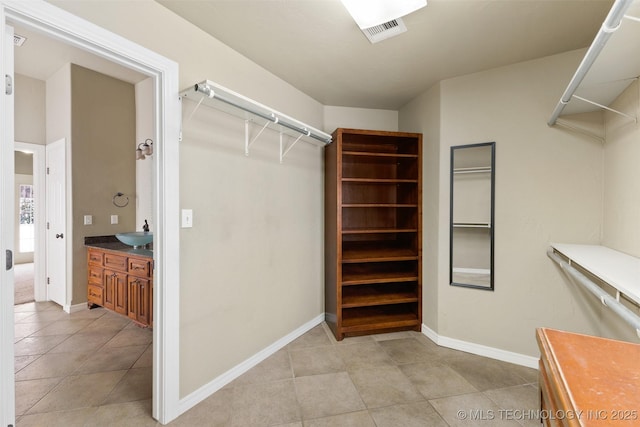 spacious closet featuring light tile patterned floors and sink