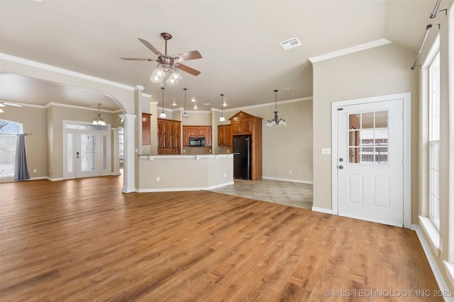 unfurnished living room with crown molding, ceiling fan with notable chandelier, and light hardwood / wood-style flooring