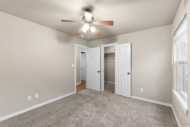 unfurnished bedroom featuring a walk in closet, light colored carpet, ceiling fan, and a closet