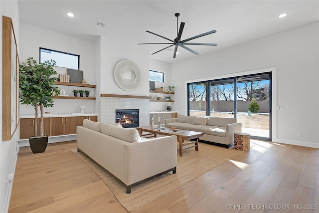 living room with ceiling fan, a fireplace, and light hardwood / wood-style flooring