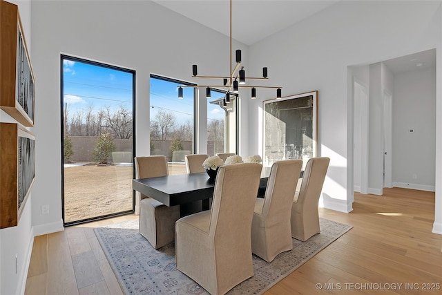 dining room featuring a chandelier, high vaulted ceiling, and light hardwood / wood-style flooring