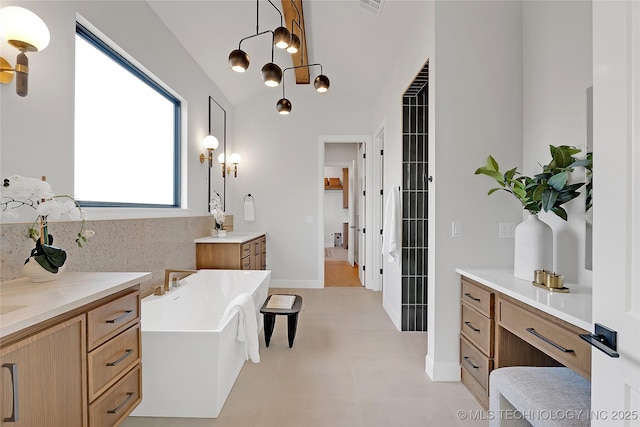 bathroom featuring a tub to relax in, vanity, and vaulted ceiling